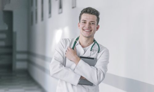 Jeune médecin généraliste en blouse souriant dans un hôpital, début de carrière en Moselle Sud