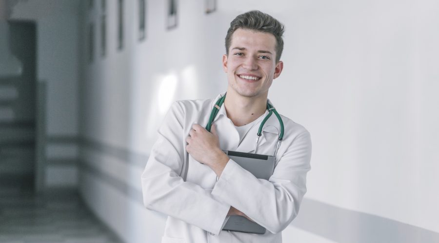 Jeune médecin généraliste en blouse souriant dans un hôpital, début de carrière en Moselle Sud